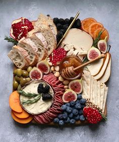 an assortment of cheeses, fruits and meats on a platter with crackers