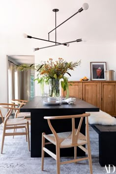 a dining room table with chairs and a vase filled with flowers on top of it