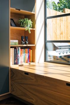 a window sill with books on it next to a wooden shelf