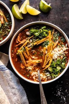 two bowls of mexican chicken soup with limes and cilantro on the side