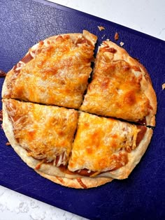 a pizza cut into four pieces on a blue cutting board