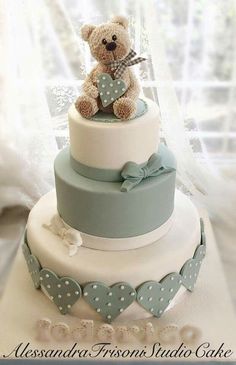 a teddy bear sitting on top of a three tiered cake with polka dot trim