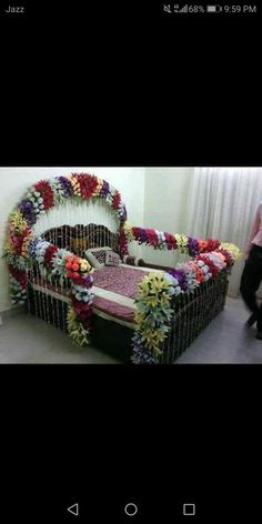 a bed made out of flowers in the middle of a room with a woman walking by