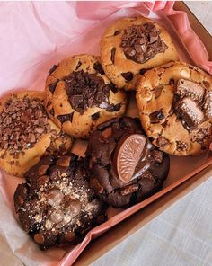 a box filled with assorted cookies on top of a pink cloth covered tablecloth