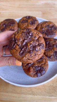 chocolate chip cookies on a plate being held by a hand