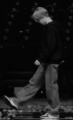 black and white photograph of a man walking in front of a wall with balls on it