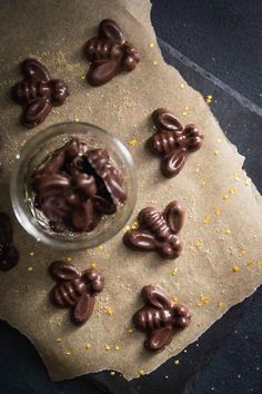 a glass bowl filled with chocolate covered pretzels on top of a piece of parchment paper