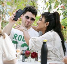 a man taking a selfie with a woman at an outdoor table in front of him