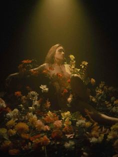 a woman sitting in the middle of flowers with her head turned to look like she's floating