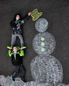 two young boys standing next to each other in front of chalk drawings on the ground