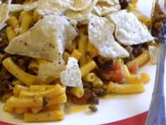 a white plate topped with pasta and tortilla shells covered in cheese, sauce and other toppings