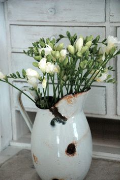 a white vase filled with flowers on top of a table