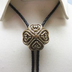 This antiqued goldtone metal heart design bolo tie would be fabulous for a wedding or for a formal occasion in lieu of a bow tie!  It is three dimensional with a modern look.  It measures 1 3/8ths inches tall and wide.  It is placed on a 36 inch long black leather string tie with golden brass metal end caps.  We put this together in our own shop - Rockin' JK Designs.  We will send this in a lovely gift box. If you like old bolo ties, western jewelry, vintage costume jewelry and silver, kindly ta Adjustable Gold Bolo Tie As Gift, Gold Adjustable Cord Bolo Ties For Gift, Gold Bolo Ties With Adjustable Cord For Gifts, Gold Bolo Ties With Adjustable Cord As Gift, Vintage Style Adjustable Bolo Ties As Gifts, Elegant Adjustable Bolo Tie As A Gift, Adjustable Elegant Bolo Ties For Formal Occasions, Elegant Adjustable Bolo Ties For Formal Occasions, Vintage Jewelry With Adjustable Length For Formal Occasions