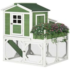 a green and white chicken coop with flowers on the roof