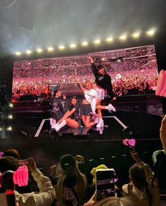 a group of people standing on top of a stage in front of a large screen