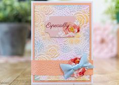 a close up of a greeting card on a table with flowers and potted plants in the background