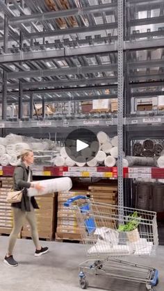 a woman walking through a warehouse with a shopping cart