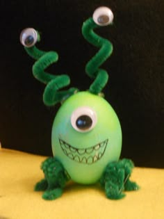 a green toy with googly eyes sitting on top of a table