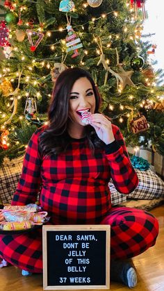 a woman sitting on the floor in front of a christmas tree and eating something out of her mouth