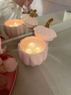 three candles sitting on top of a table next to other items in front of a mirror