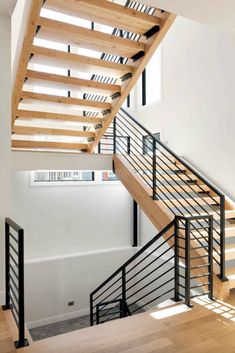 a wooden staircase with black railing and handrails in an empty room next to a white wall