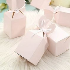 four pink boxes with bows on them sitting on a white furnishing area next to flowers