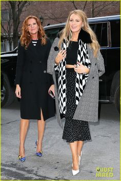 two women in black and white outfits are walking down the street with one woman wearing blue heels