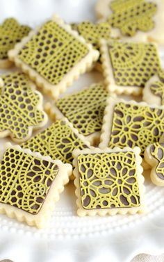 some cookies that are on a plate with white and yellow icing in the shape of squares