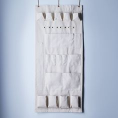 a white bag hanging on a blue wall with clothes pins attached to the front and sides