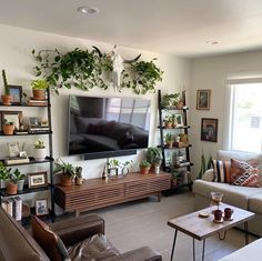 a living room filled with furniture and lots of greenery on the wall above it