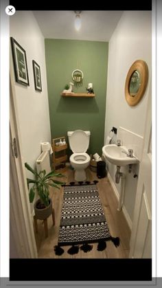 a small bathroom with green walls and white fixtures, including a rug on the floor