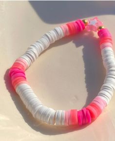 a white and pink bracelet with gold accents