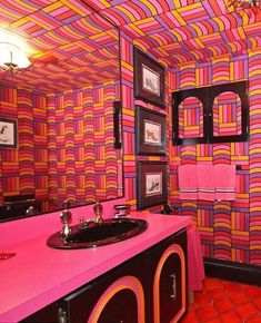 a bathroom with pink and orange wallpaper on the walls, black sink and mirror