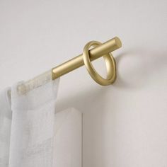 a curtain rod with a gold ring on the end is hanging in front of a white wall