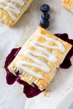 a piece of pie with white icing and blueberries on the side next to it