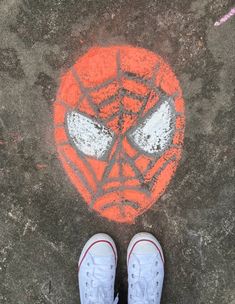 someone is standing in front of a spider man drawing on the sidewalk with chalk and markers