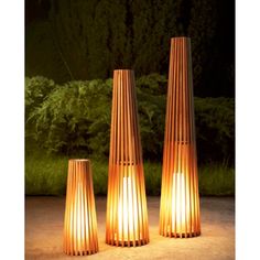 three tall wooden lamps sitting on top of a cement ground