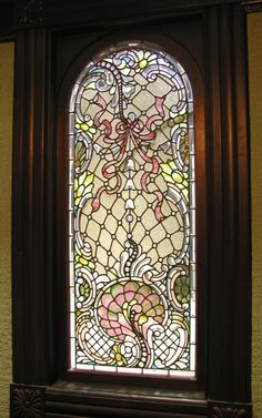 an ornate stained glass window in the corner of a room with wood trimmings