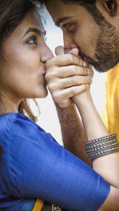 a man and woman holding each other close to their foreheads as they look at each other