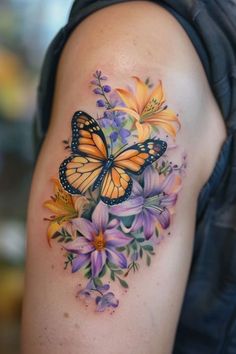 a butterfly and flowers tattoo on the right arm, with purple daisies in the background