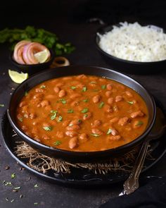 a black bowl filled with beans and rice on top of a table next to other dishes