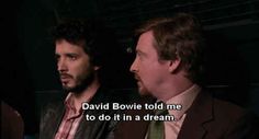 two men sitting next to each other in front of a dark background with the words david bovie told me to do it in a dream