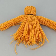 an orange tasseled object on a gray surface with yellow thread in the middle