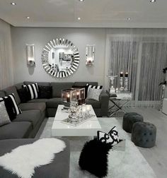 a living room filled with gray couches and white coffee table in front of a mirror