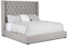 a bed with white sheets and pillows on top of it's headboard is shown