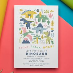 an image of dinosaur birthday party card on colorful paper with crayon pencils next to it