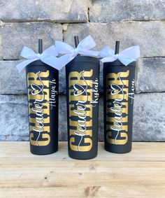 three black and gold tumblers with white bows on them sitting next to each other