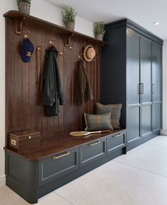 a wooden bench sitting next to a wall filled with coat hooks and hats on top of it