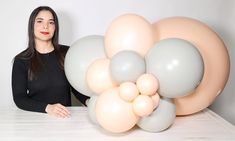 a woman standing next to a bunch of balloons on top of a white countertop