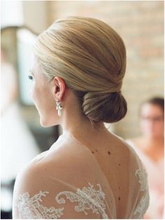 a woman with her hair in a low bun is looking off into the distance while wearing earrings